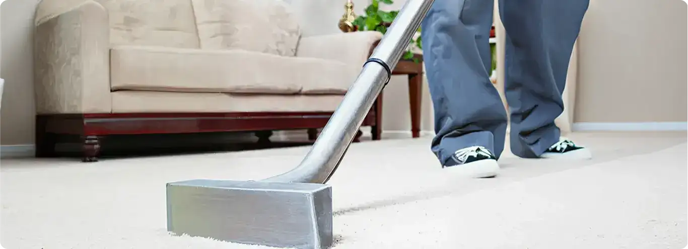 Carpet cleaning technician using a hot-water extraction wand on a light-colored carpet in a living room, Kansas City, MO.
